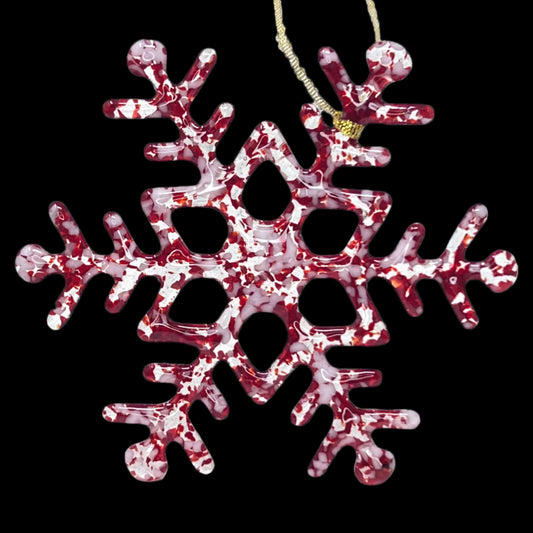 A handcrafted glass snowflake ornament with a mix of red, white, clear, and iridized glass, designed to be used as a Christmas decoration.